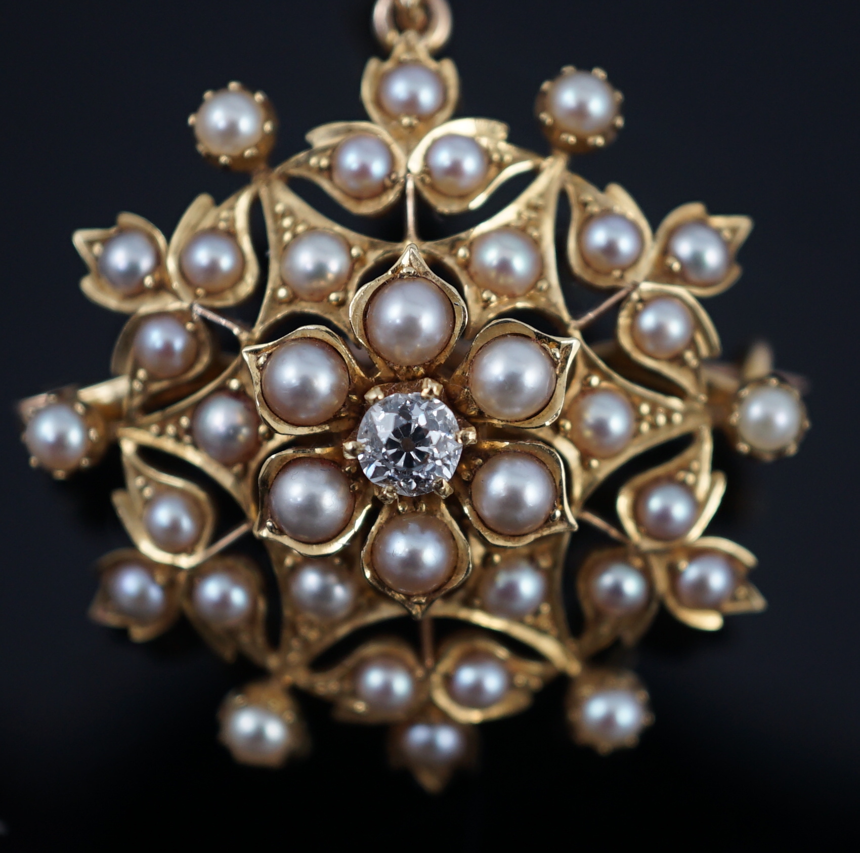 An Edwardian single stone diamond and seed pearl cluster set pendant brooch